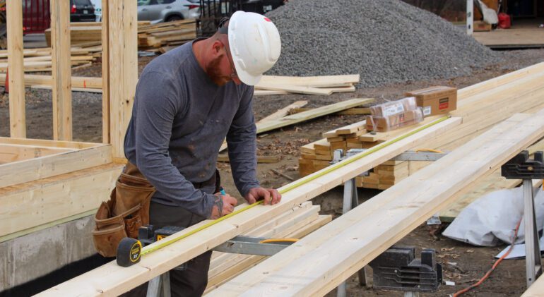 MDI worker carefully measuring lumber for new construction, showcasing expertise in home building by MDI Homes.
